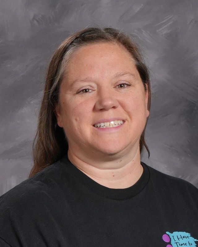 A woman with long hair and wearing a black shirt is smiling for the camera.