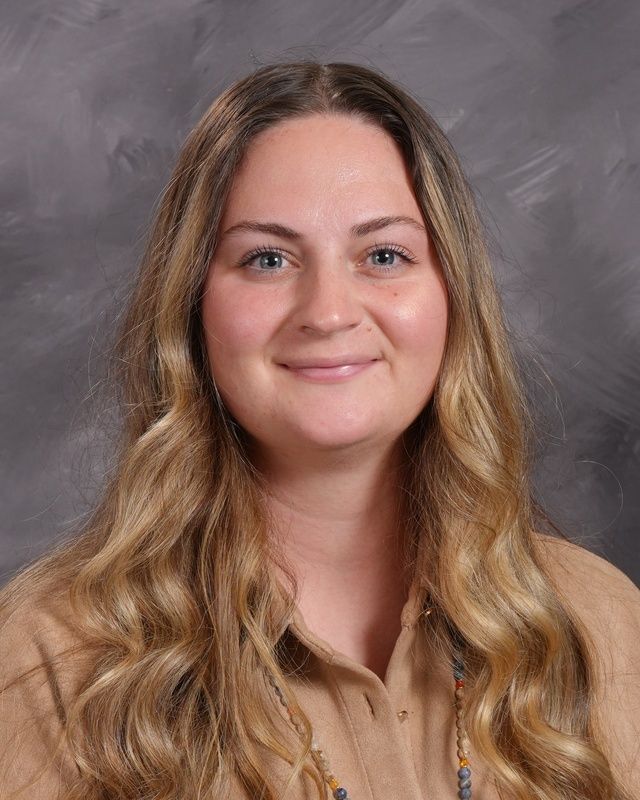 A woman with long hair wearing a white sweater smiling for the camera