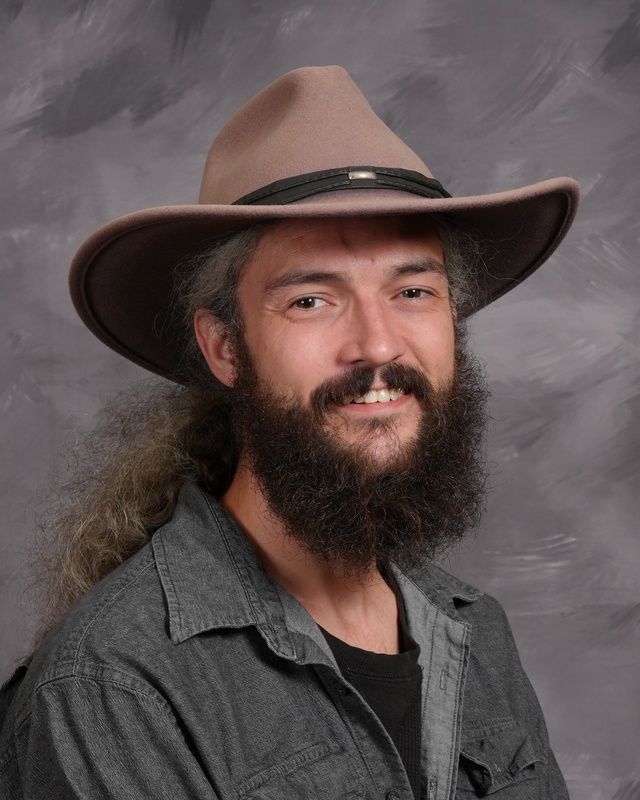A man with a full beard and glasses smiling for the camera