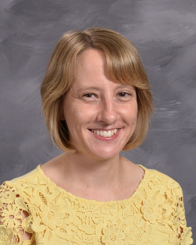 A women wearing a yellow shirt smiling for the camera