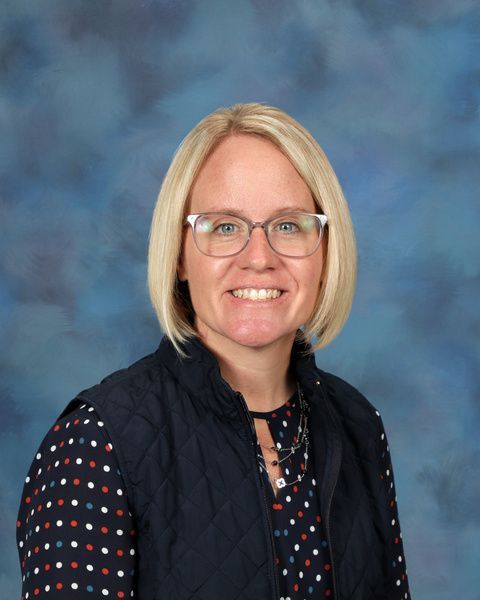Woman with short blonde hair and glasses smiling for the camera