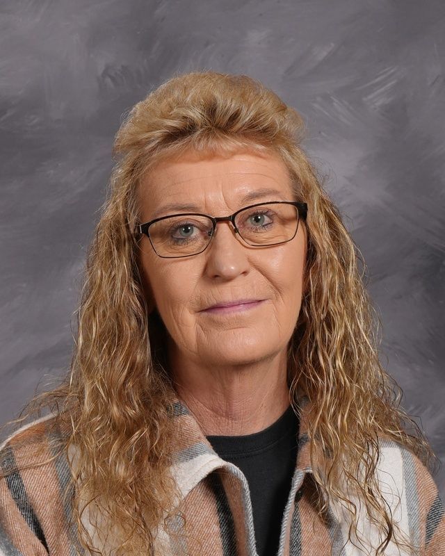 A woman wearing glasses and a black sweater poses for a picture