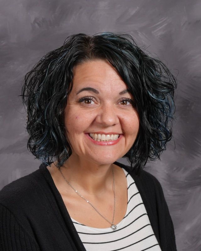 A woman wearing a black and white striped shirt smiles for the camera
