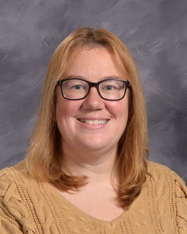 A woman wearing glasses smiles for the camera