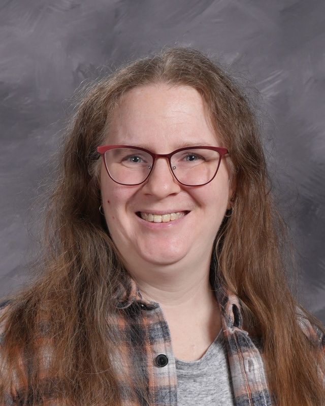 Woman with long hair and glasses smiles for the camera