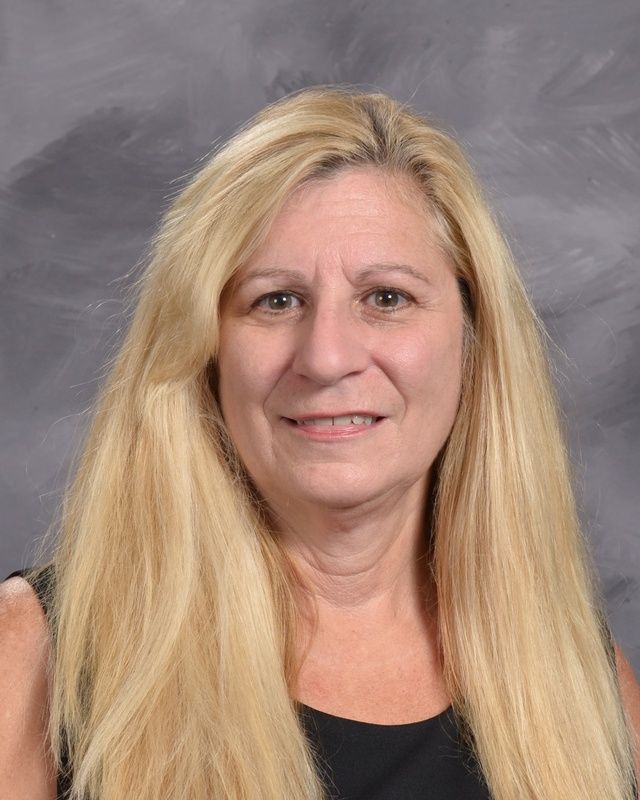 A woman with long blonde  hair wearing glasses and a black shirt smiles for the camera
