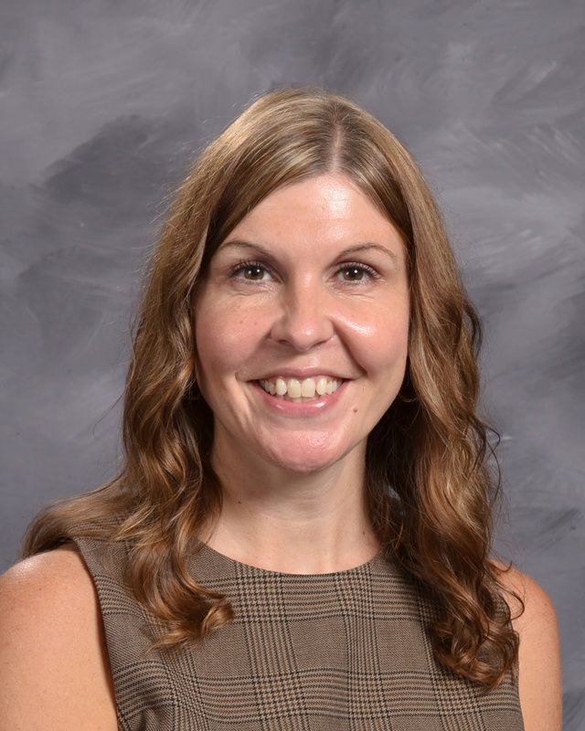 A woman wearing a brown sleeveless shirt smiles for the camera