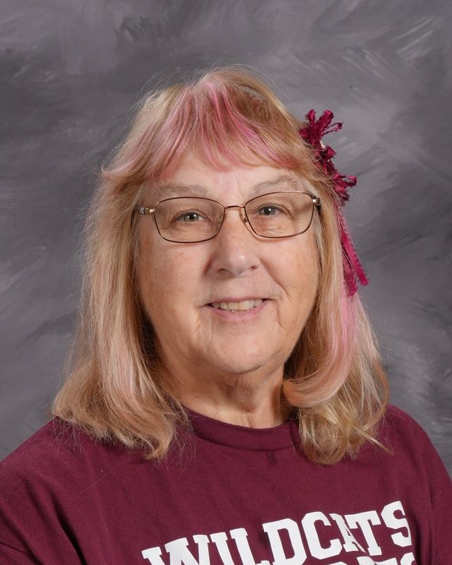 A woman wearing glasses and a colorful shirt smiling for the camera