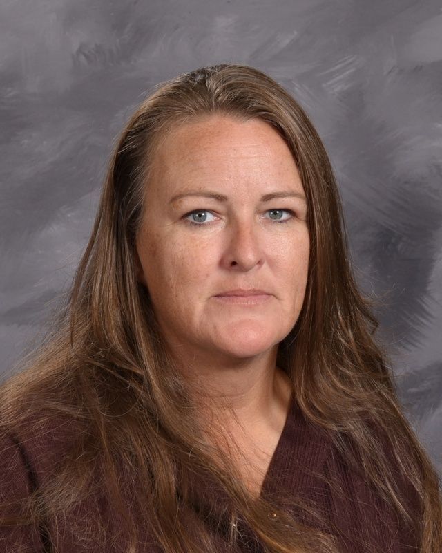 A woman in a brown shirt is smiling for the camera