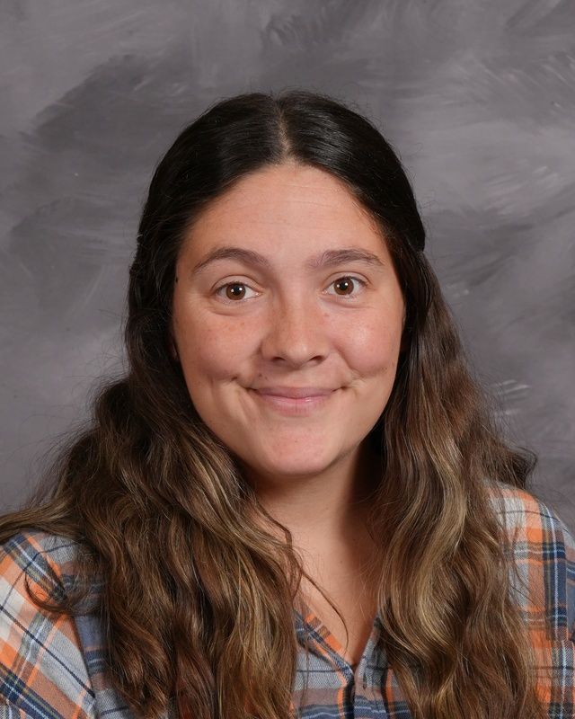 A woman with long hair and wearing a white sweater smiling for the camera
