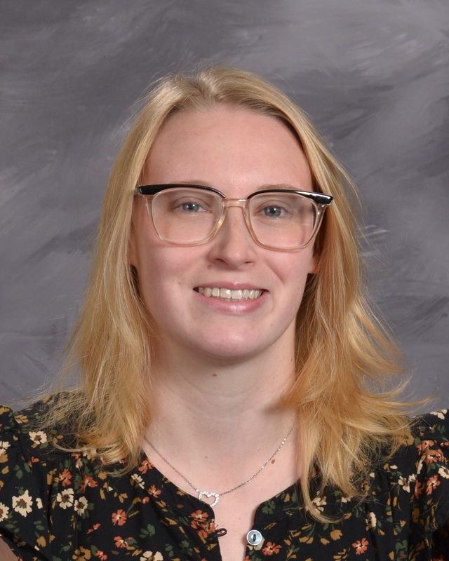 A woman wearing glasses and a black shirt smiles for the camera