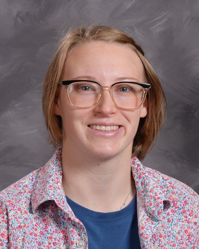 A woman wearing glasses and a black shirt smiles for the camera