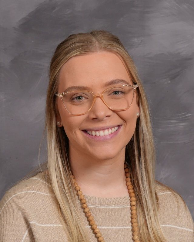 Women with long hair and wearing glasses and a green shirt smiling for the camera