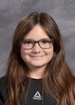 A young girl wearing a black t-shirt and glasses smiling for the camera