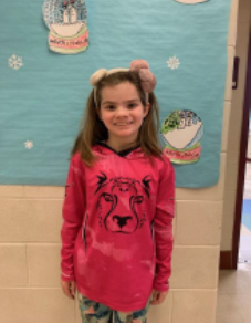 A young girl wearing a ping shirt smiling for the camera