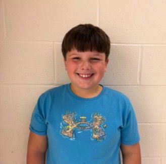 A young boy in a blue t-shirt smiling for the camera