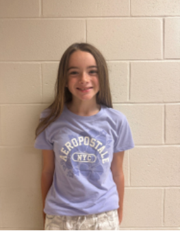A young girl with long dark hair wearing a purple Aeropostale t-shirt smiling for the camera