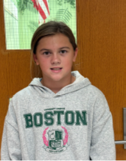 Young girl with dark hair wearing a grey Boston hoodie smiling for the camera