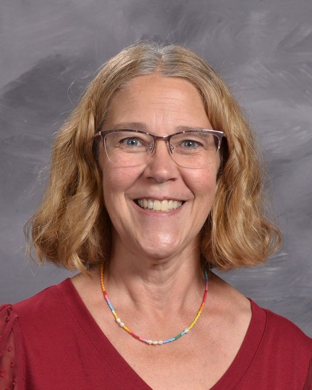 A woman wearing glasses and a red shirt smiling for the camera