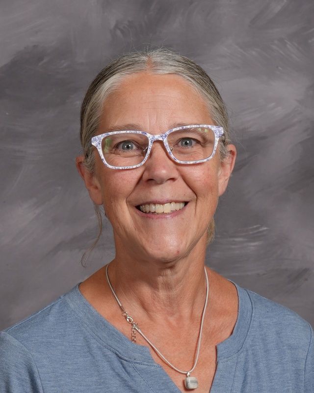A woman wearing glasses and a red shirt smiling for the camera