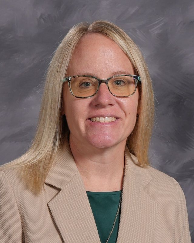 Women with short blonde hair and glasses smiling for the camera