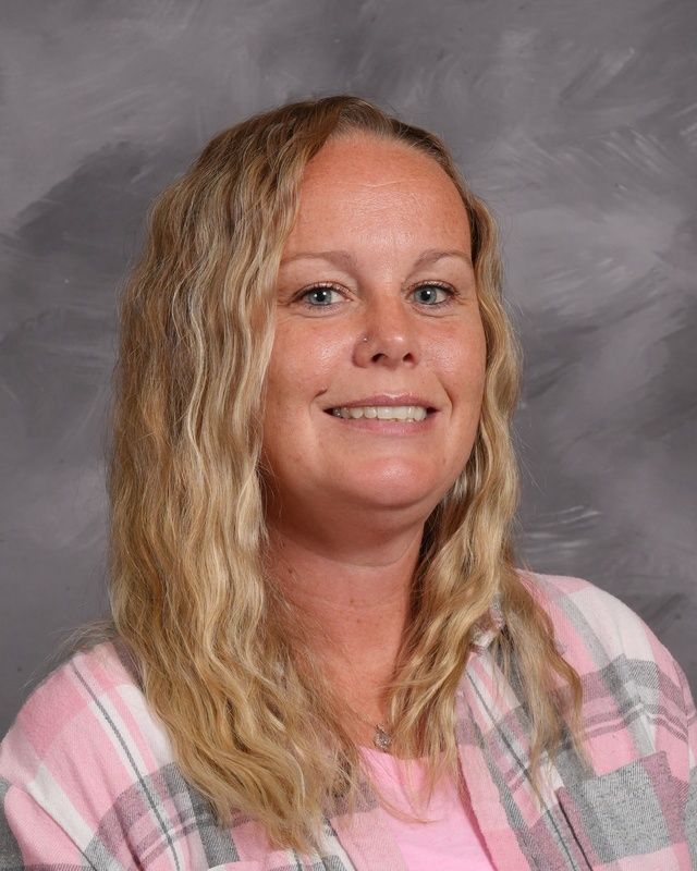 A woman in a blue sweater is smiling for the camera