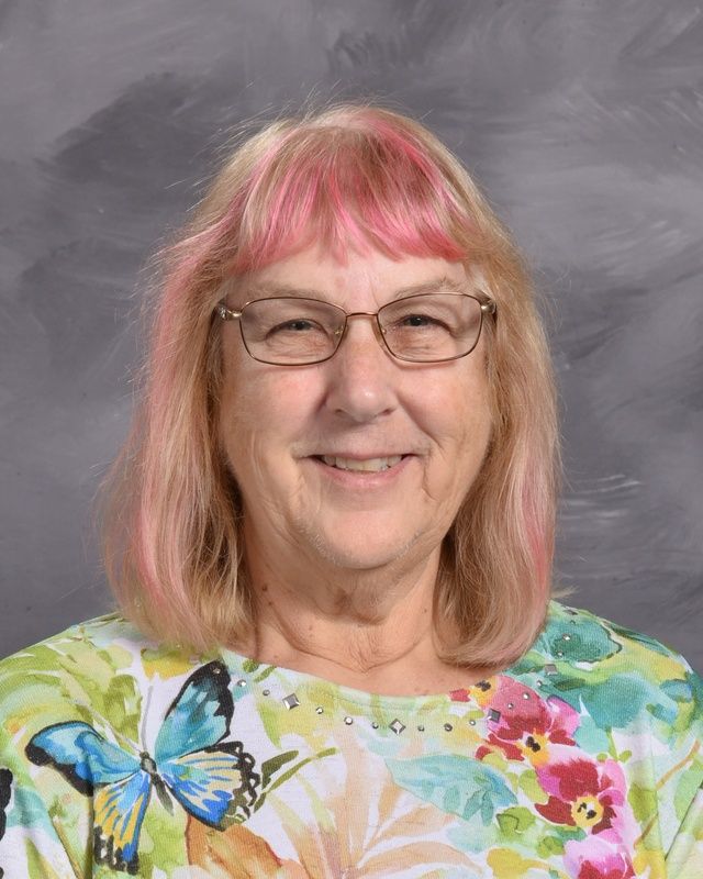 A woman wearing glasses and a colorful shirt smiling for the camera