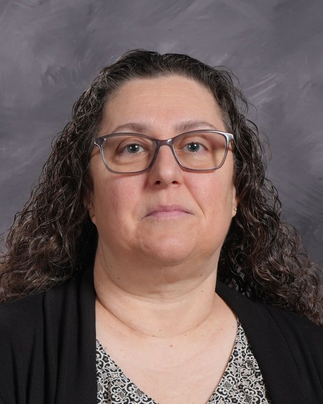 A woman wearing glasses and a black shirt smiles for the camera