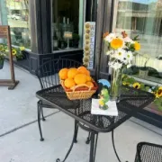 Table with oranges, flowers, and a “Welcome” sign outside a storefront