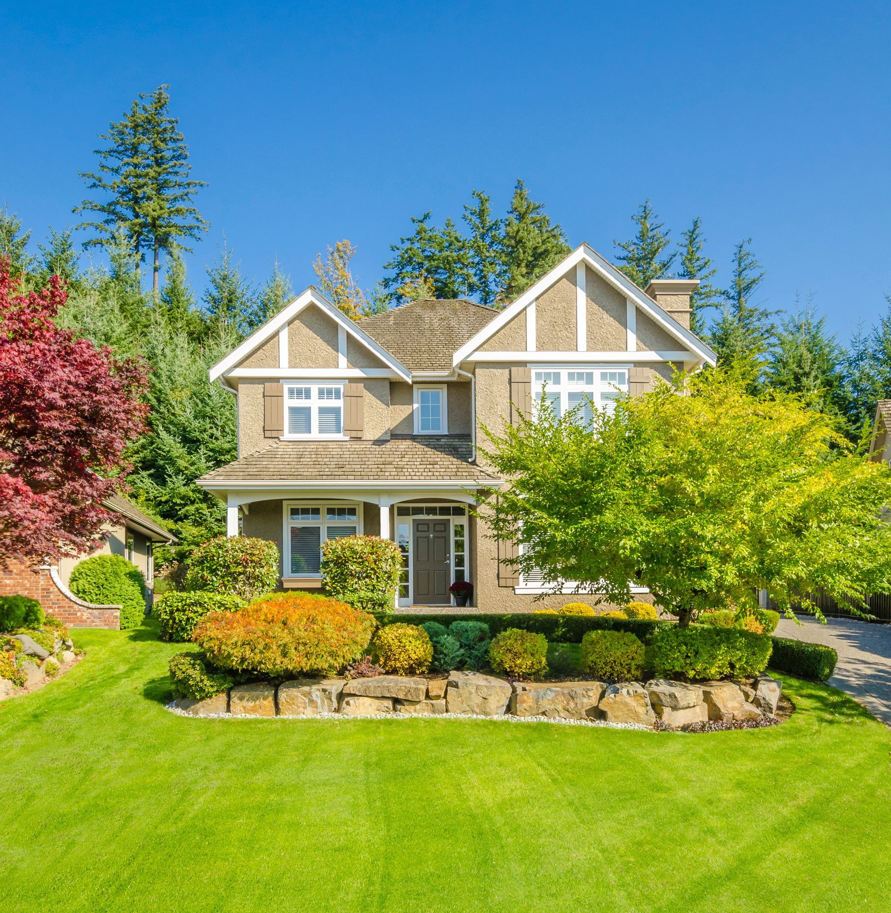 A large house with a lush green lawn and trees in front of it. A large house with a lush green lawn and trees in front of it.