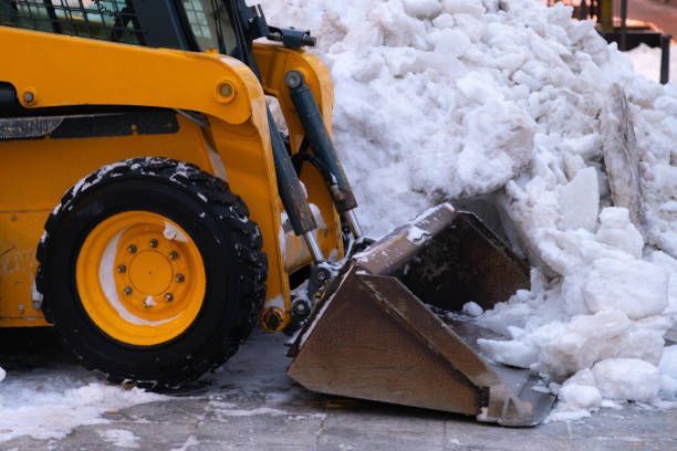 A yellow snow plow is clearing snow from the sidewalk.
