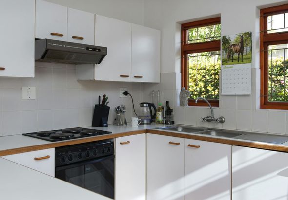 Bright white kitchen with wooden countertops, black stove, and a window over the sink.