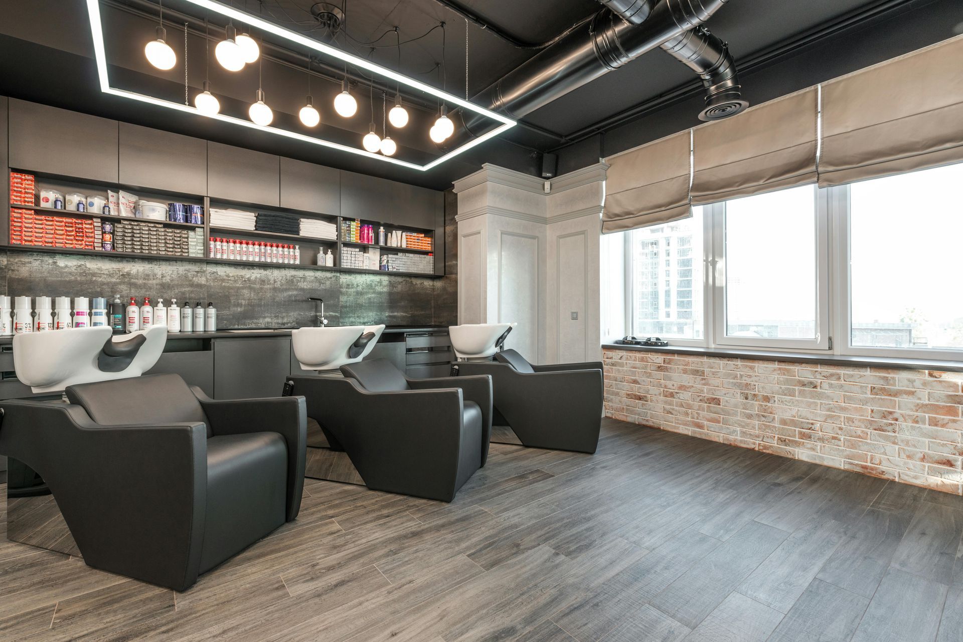 Modern lounge with black armchairs, built-in shelves, and large windows in an industrial-style room