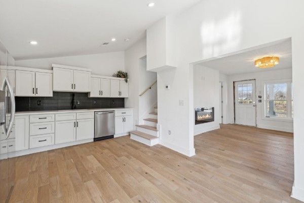 A kitchen with white cabinets and hardwood floors