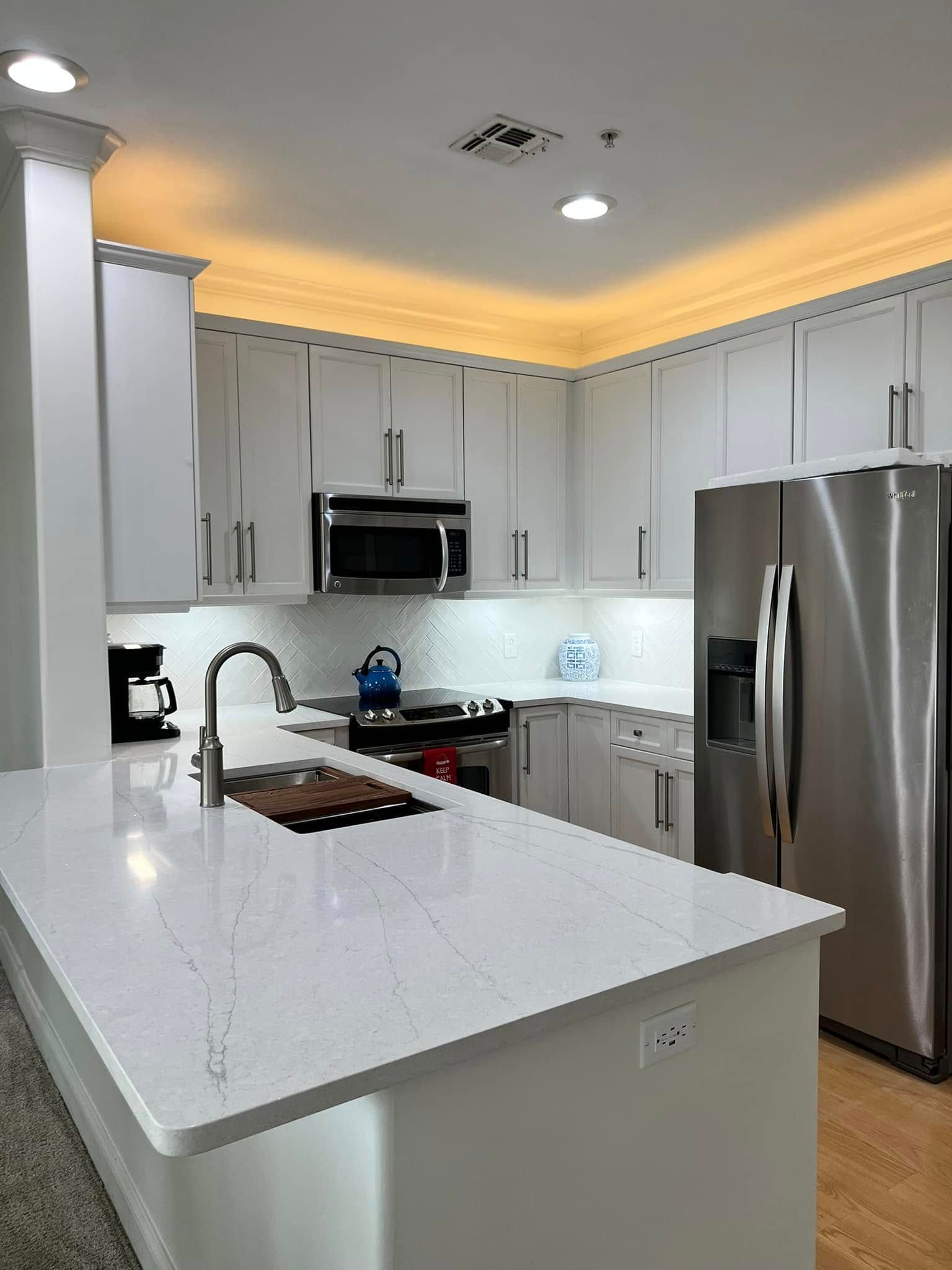 A kitchen with white cabinets, stainless steel appliances, and a large island