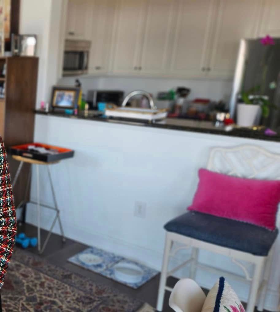 A chair with a pink pillow sits in front of a kitchen counter