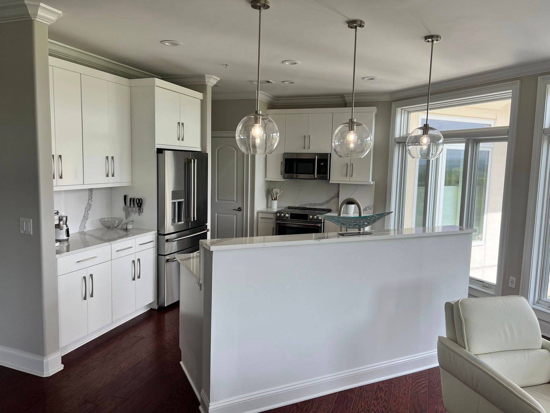 A kitchen with white cabinets, stainless steel appliances, and a large island