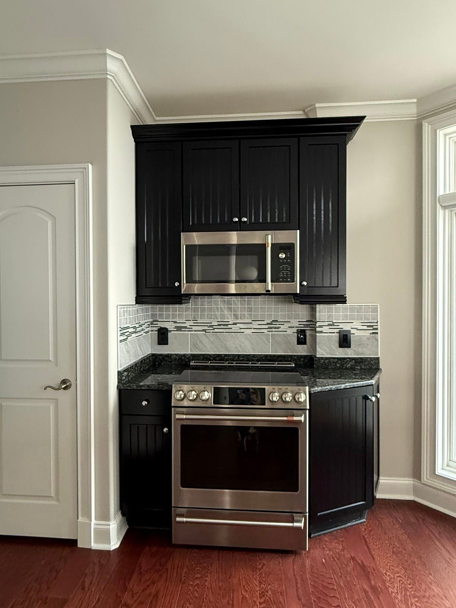 A kitchen with black cabinets and stainless steel appliances