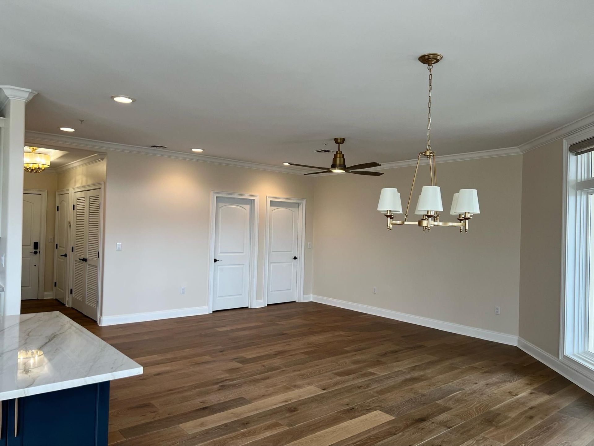 An empty living room with hardwood floors and a ceiling fan