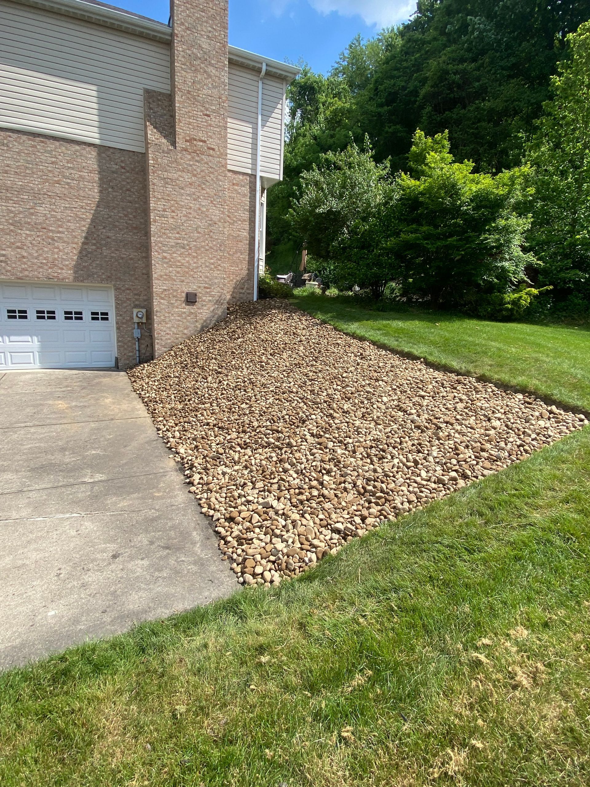 A large pile of gravel is sitting in front of a house.
