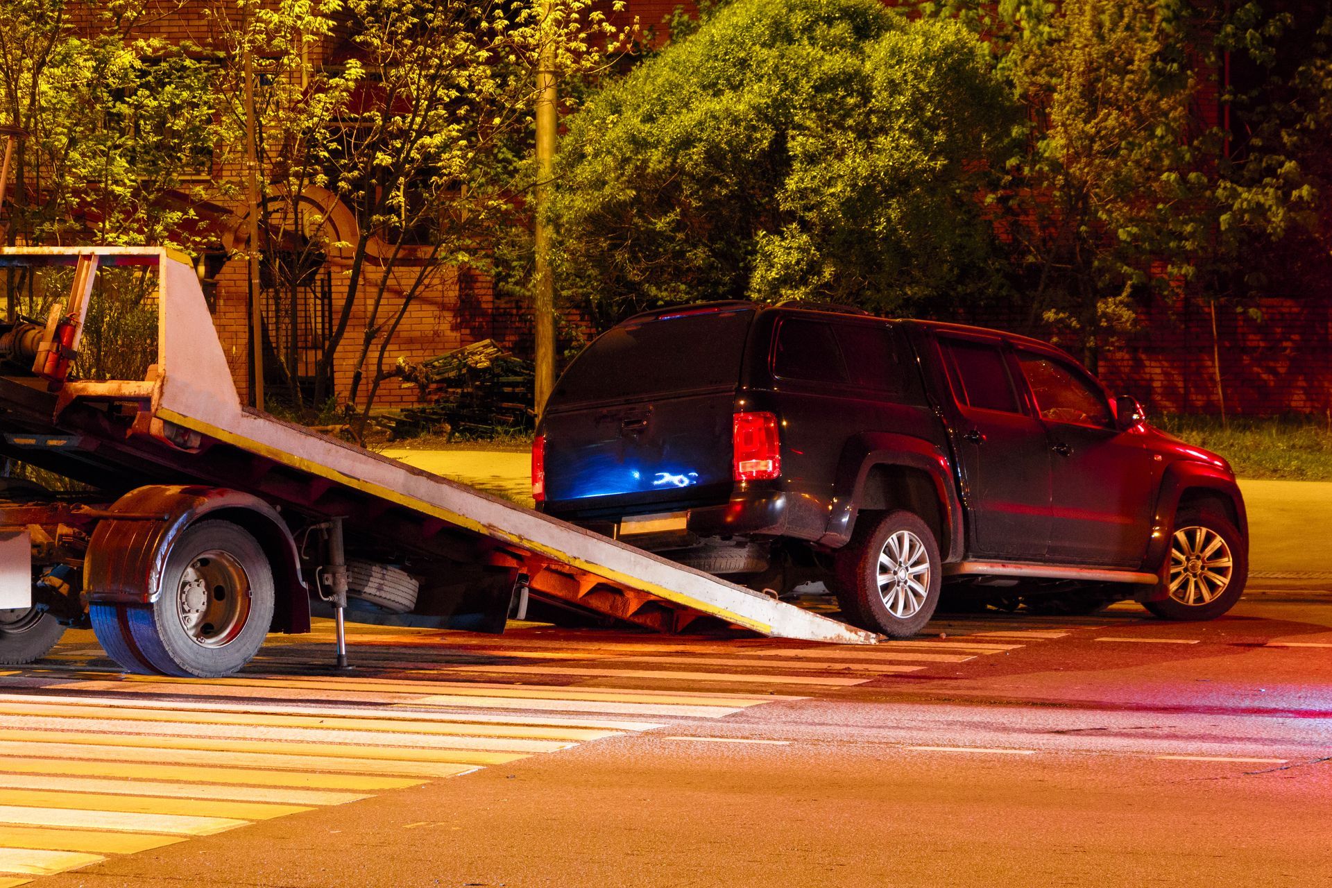 tow truck loading black SUV for towing at night