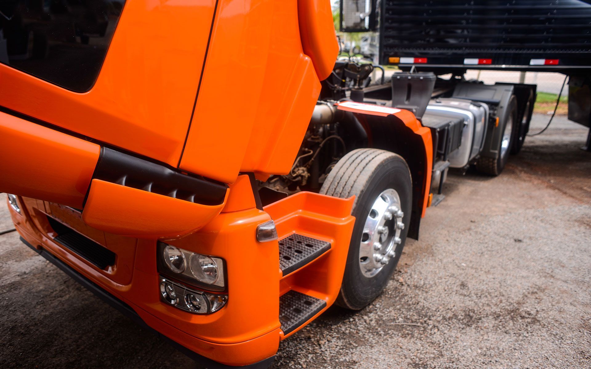 Orange semi-truck front with hood open.