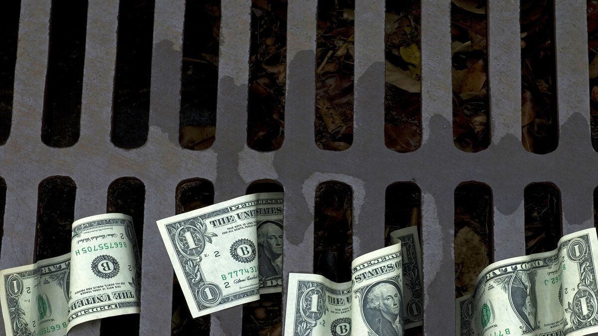 U.S. dollar bills caught in a storm drain grate