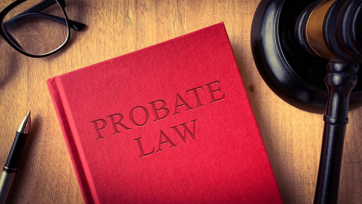 Red probate law folder beside a gavel and eyeglasses on a desk