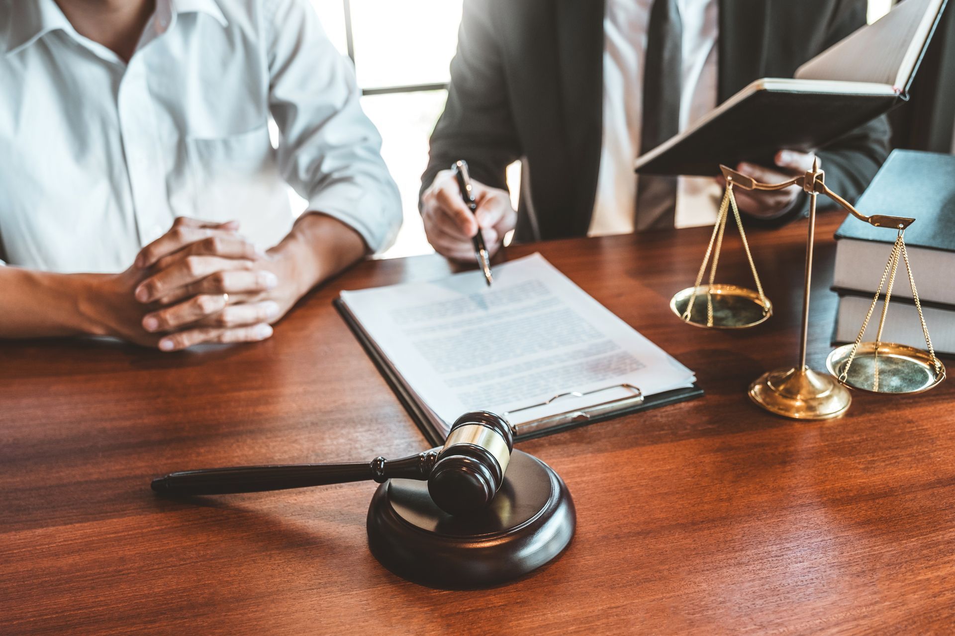 Two Men Are Sitting at a Table With a Gavel and Scales of Justice