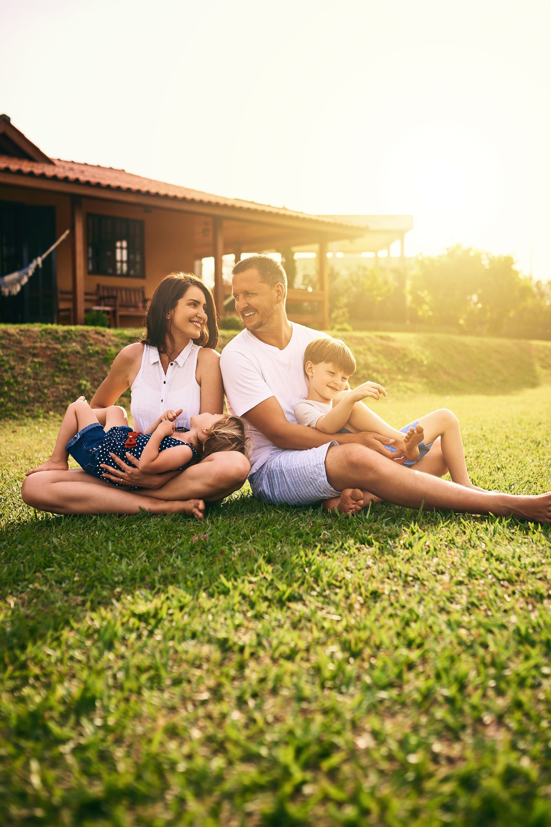A Family is Sitting on the Grass in Front of a House