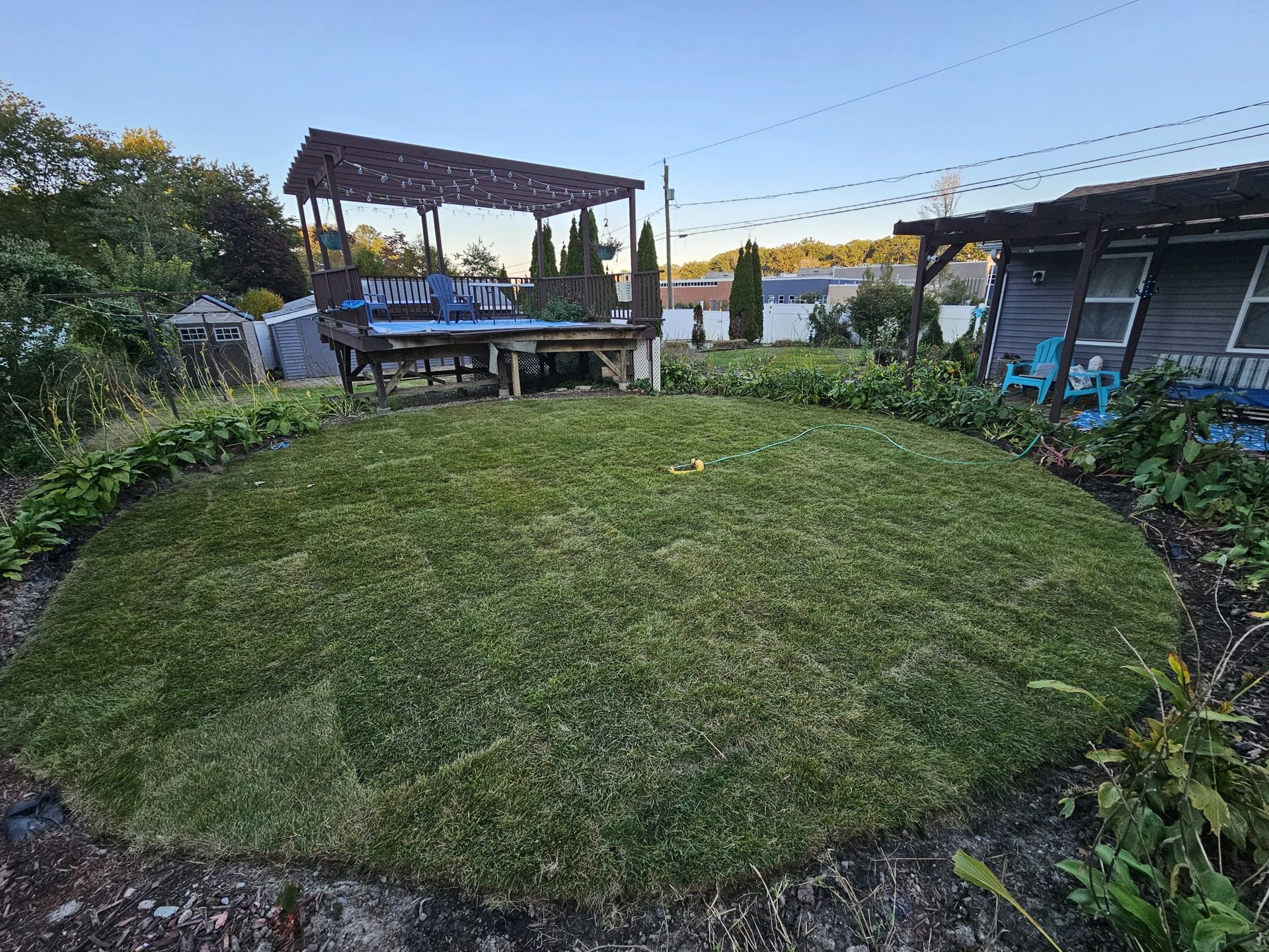 A wooden picket fence surrounds a lush green lawn in front of a house