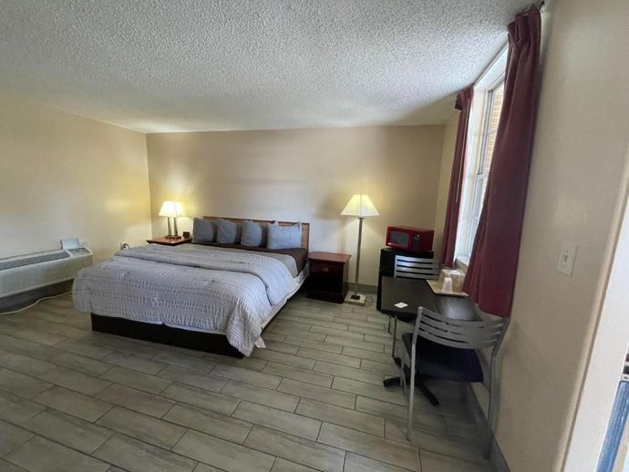 A hotel room with a king size bed , desk and chairs.