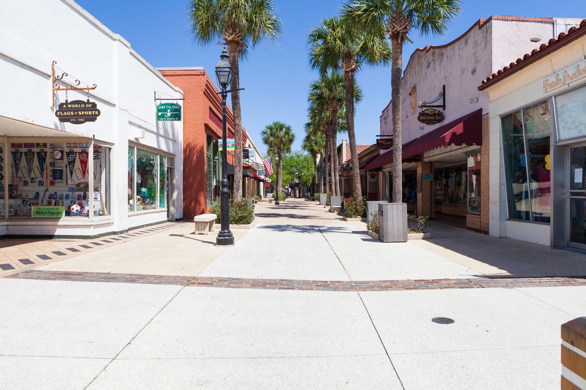 A row of stores are lined up on a sidewalk in a small town.