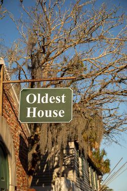 A sign for the oldest house hangs from a tree.